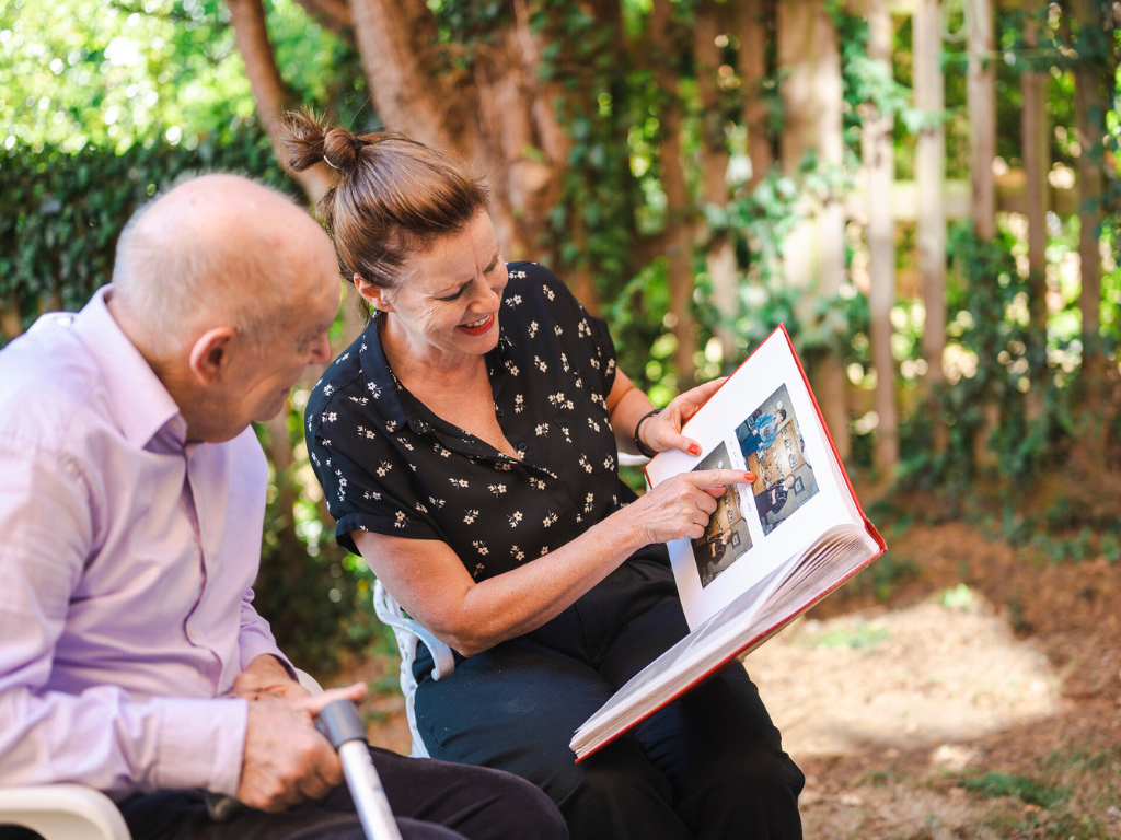 Ann and her father look at a photo album while sitting outside