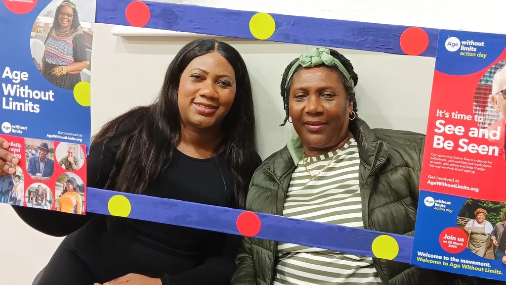 Two women pose next to an Age Without Limits banner in Doncaster