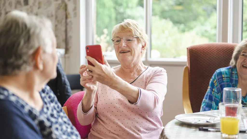 A woman takes a picture of another woman using her phone