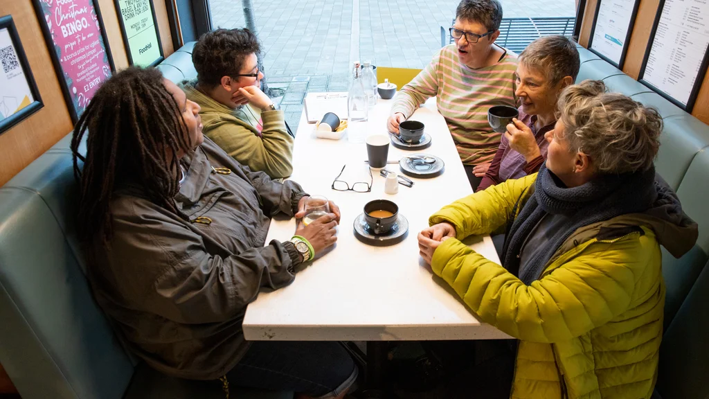 A group of women sit at a cafe table and talk