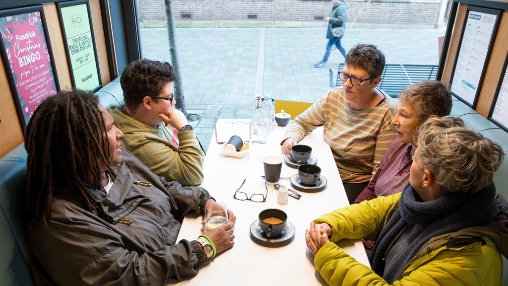 Five women talking at a cafe