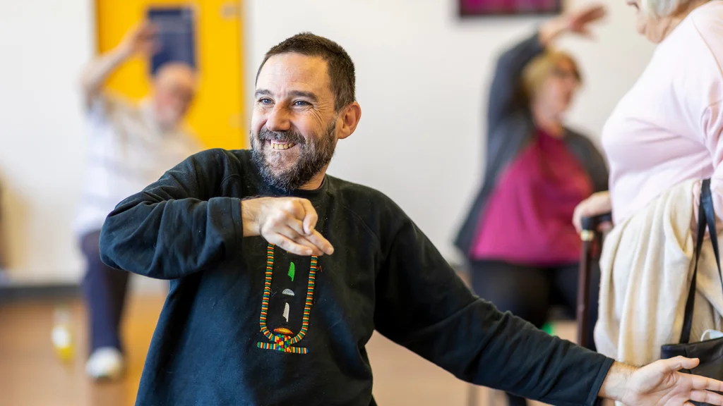 A man doing exercises in a class with other people in the background