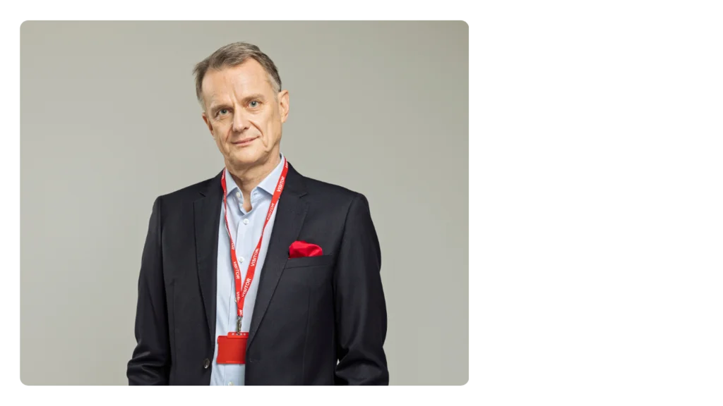 A man wearing a suit and a red lanyard marked with the word visitor