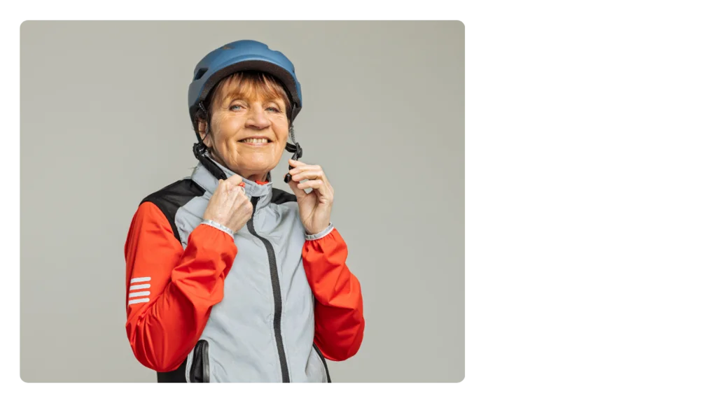 A woman in an exercise jacket putting on a helmet